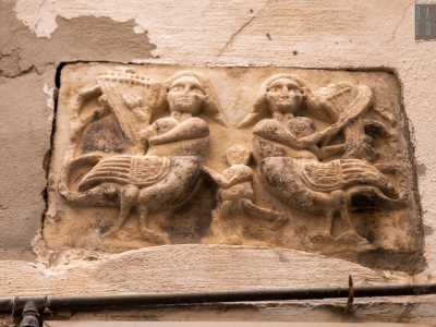 L'immagine ritrae due arpie, creature mitologiche met� donna e met� uccello legate al regno simbolico del male e dell�avidit�. Le figure, rappresentate con volto serioso e con delle lunghe code, sono intente a suonare strumenti musicali: un�arpa e una specie di violino. Al centro invece � raffigurato un fanciullo nudo privo di volto che tende il braccio sinistro verso una delle due